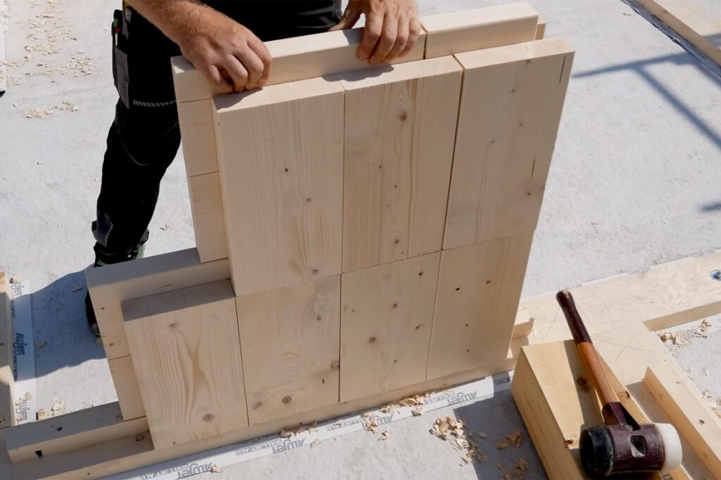 Solid wood blocks stack together to create walls without nails or adhesives.