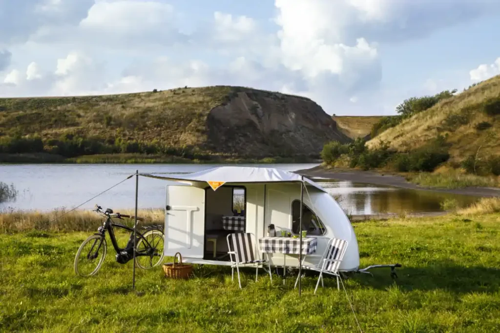 A fold-out camper with bed, table, and windows.